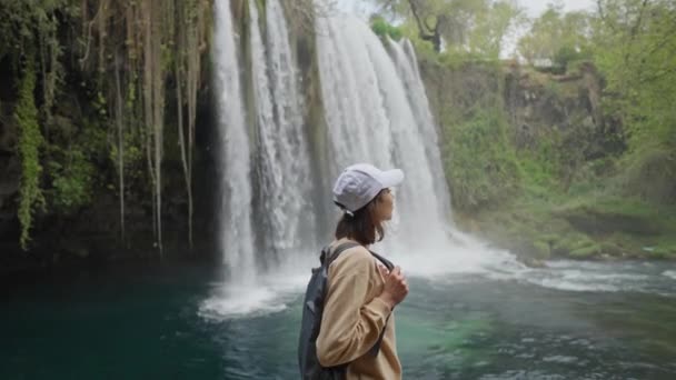 Retrato de feliz hermosa joven turista en el fondo de la cascada de Duden superior enorme en Antalya. Punto de vista famoso y lugar turístico en Turquía. — Vídeo de stock