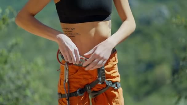 Junge Frau mit schlankem Körper, die sich auf das Klettern vorbereitet, Gurtzeug und Ausrüstung anlegt. Gesunder Lebensstil und Fitness. — Stockvideo