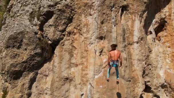 Flygfoto från drönare av stark atletisk man bergsklättrare nedstiger från hög vertikal klippa på övre rep. hälsosam livsstil och idrott utomhus i Turkiet. 4k stok-bilder — Stockvideo