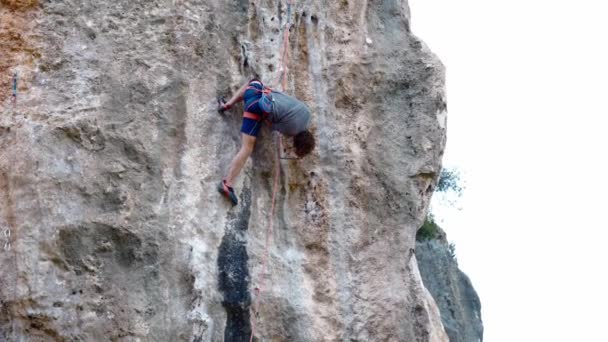 Alpinist puternic și priceput urcă pe verticală crag calcar prin traseu provocator, alpinist este în poziție de genunchi au o odihnă bună pentru mâini, scuturând mâinile pentru îmbunătățirea circulației sângelui — Videoclip de stoc