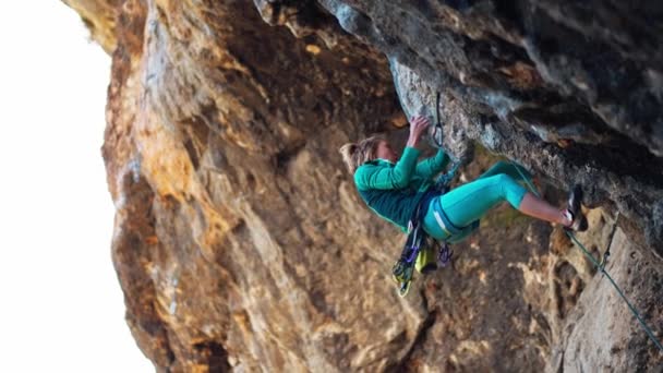 Una donna forte arrampicatrice arrampica su roccia dura su una scogliera nera molto strapiombante in Turchia. — Video Stock