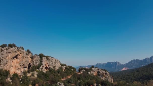 ドローンからの空中ビューは、ロッククライミングエリアと登山者のためのキャンプを飛んでいます。アンタルヤと岩の山の尾根上の青い空と美しい景色. — ストック動画