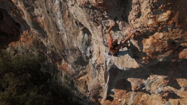 Antenn drönare POV av stark muskulös man klättring utmanande rutt på vertikal spricka med tufa. klättrare når handtag och gör lång hård rörelse och ansträngning. — Stockvideo