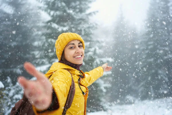 Szczęśliwa radosna kobieta w zimowym lesie z opadającym śniegiem. Świąteczne wakacje na świeżym powietrzu — Zdjęcie stockowe
