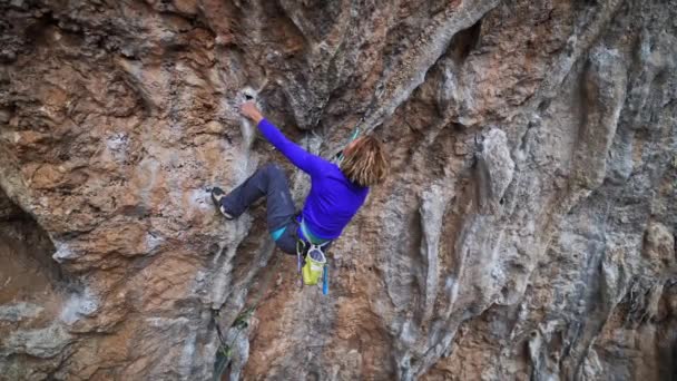 Bergsteigerin in Zeitlupe auf überhängender Klippe. Bergsteigerin versucht auf anspruchsvoller Route, Tuffstein-Griffe zu greifen. — Stockvideo