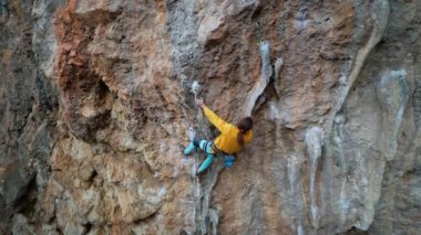 Hava ağır çekim geri görüş güçlü kaya tırmanıcı koloni ile kireç taşı uçurumuna tırmanır
