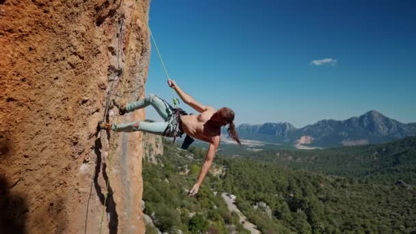 Strong and muscular fit rock climber hangs on rope on vertical cliff.  handsome man with naked