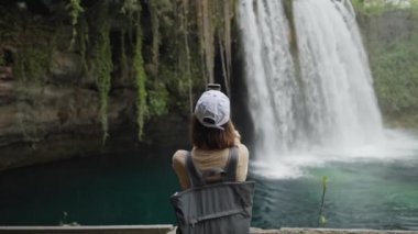Antalya 'da Duden Şelalesi' nin arka planında cep telefonuyla selfie çeken çekici gülümseyen kadın turist. Türkiye 'de ünlü manzara ve turistik yer.