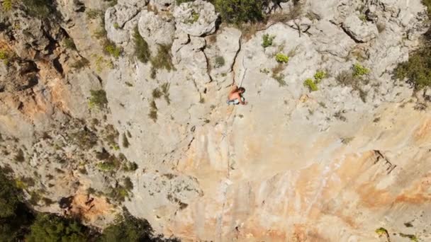 Flygbilder. vy från drönare av stark muskulös man klättrar utmanande bergsklättring rutt på vertikal kalksten spricka — Stockvideo