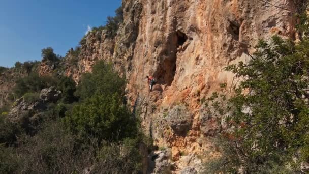 Drone vliegend langs kalkstenen klif met rotsbeklimmer erop. man klimt uitdagende route op verticale crag — Stockvideo