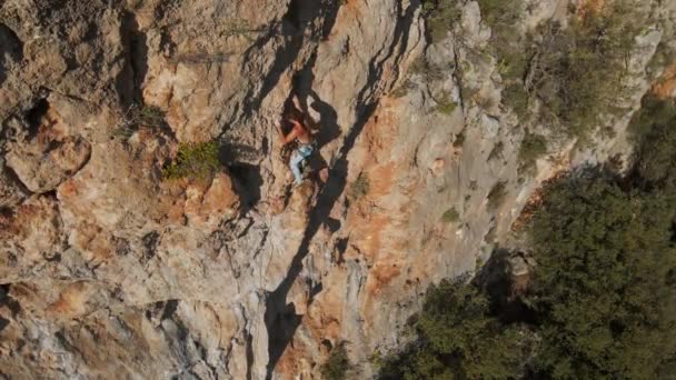 Lucht drone POV van sterke gespierde man klimmen uitdagende route op verticale crag met tufa. klimmer bereikt handgrepen en maakt lange harde beweging en inspanning. — Stockvideo