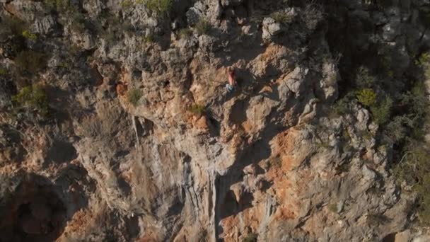 Εναέρια άποψη από drone του ισχυρού μυώδης άνθρωπος ανεβαίνει προκλητική αναρρίχηση διαδρομή. ορειβάτης φτάνει handholds και κάνει μακρά σκληρή κίνηση — Αρχείο Βίντεο