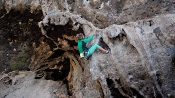 Fuerte escalador de roca mujer tratando de escalar la ruta dura roca dura en acantilado sobresaliente — Vídeos de Stock