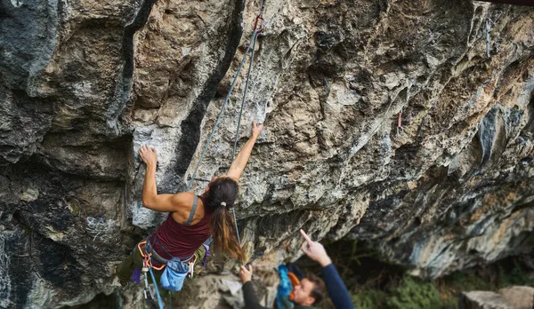 Forte donna sportiva che si allena all'aperto, inizia a scalare la dura via sulla roccia — Foto Stock