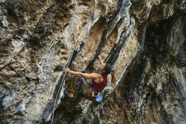 Starke selbstbewusste Frau, die auf Felsen klettert und sich auf das Streben nach dem Ziel konzentriert — Stockfoto