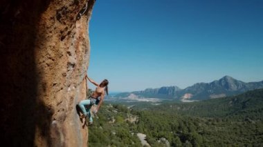 Kas yığını, parlak mavi pantolonlu kaya tırmanışçısı Türkiye 'deki uçurumun zorlu yoluna tırmanıyor. güçlü çekici kaya tırmanışçısı kayalık kireçtaşı bir duvara tırmanır, yan görünüm