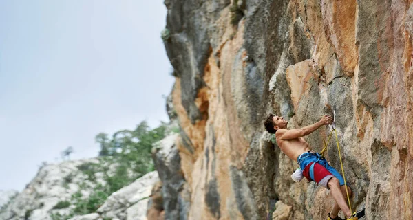 Passform och fokuserad atletisk man klättring utmanande rutt på hög vertikal klippa — Stockfoto