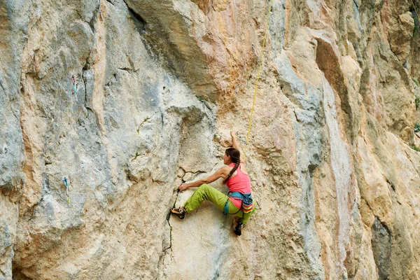 Visão traseira alpinista mulher escalando na bela parede de rocha em rota desafiadora — Fotografia de Stock