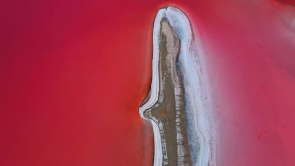 Epicki lot dronem nad pięknym różowym słonym jeziorem z głęboką, spokojną powierzchnią wody i małą wyspą ze złożami soli — Wideo stockowe