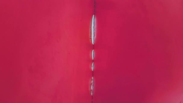 Vista cinematográfica superior aérea sobre belo lago de sal rosa com superfície de água calma colorida profunda e pequenas ilhas com depósitos de sal — Vídeo de Stock