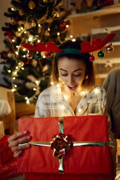 Zaskoczona uśmiechnięta kobieta otwierająca prezent świąteczny, zaglądająca do pudełka — Zdjęcie stockowe