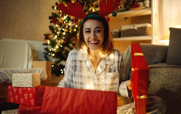 Portret śmiech patrząc szczęśliwa kobieta otwierając pudełko świąteczne w domu — Zdjęcie stockowe