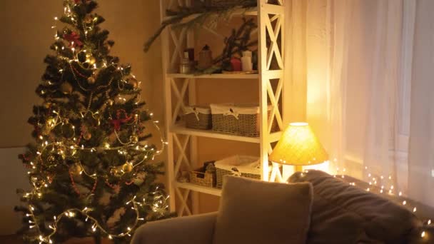Рождественские елки украшения и подарочные коробки в номере ночью. Удивительные сверкающие гирлянды, излучающие дух Рождества и настроение. Темная комната с новогодними украшениями — стоковое видео