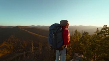 Dağın tepesinde neşeli bir kadının yavaş çekimleri. Güzel manzaranın tadını çıkarıyor. Kolları açık, kanyon ulusal parkında yürüyüş yapıyor.