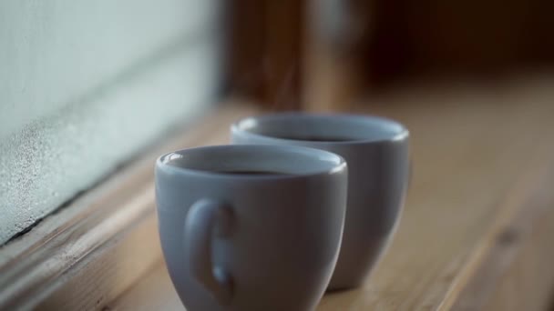 Close up side view Két csésze forró ital kávé ablak mellett, víz páralecsapódás ablak üveg, kora reggel, ébredés koncepció — Stock videók