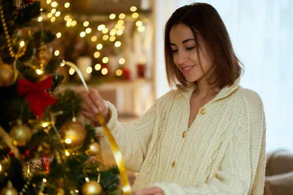 Nainen koristaa joulukuusi kotona päätöksenteossa, juhlii joulu ja onnellista uutta vuotta — kuvapankkivalokuva