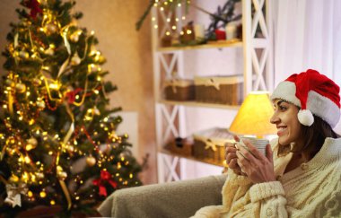 Mutlu Noel Kadın elinde bir fincan çayla Noel ve yeni yılda mucizelerin gerçekleşmesini bekliyor.