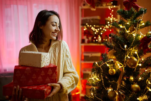 Munter kvinne i dekorert rom ved juletreets gavebokser – stockfoto