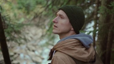 Ormanda yürüyüş yapan bir adamın portresi. Yorgun ve esinlenilmiş seyahat eden erkek sırt çantasıyla ormanda ve nehirde