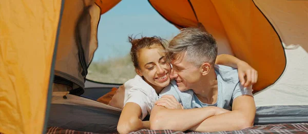 Turistit pari rentoutua yhdessä oranssi teltta. Suhteet, leirintäelämä — kuvapankkivalokuva