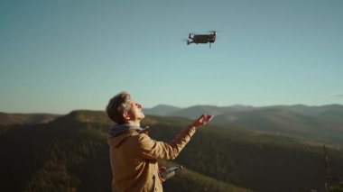 Vahşi doğada uzaktan kumandalı bir erkek pilot. Profesyonel hava fotoğrafçısı ve İHA operatörü uçuştan sonra İHA 'yı eline indirip filme çekiyor. Çam ormanı ve dağ manzarası