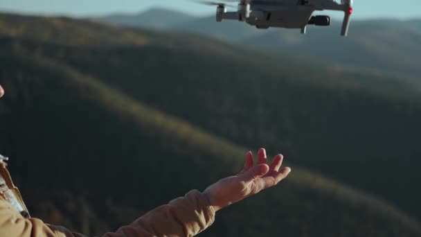 Mão de perto do operador de drone profissional e fotógrafo aéreo pousando drone em sua mão após o voo e as filmagens. Pinhal e paisagem de montanha no fundo — Vídeo de Stock