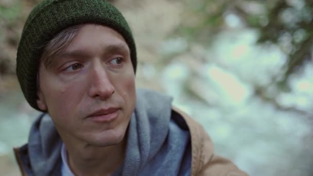 Portré egy férfi túrázóról, aki az erdőben sétál. fáradt és inspirált utazó férfi hátizsák egy erdő és folyó háttér — Stock videók
