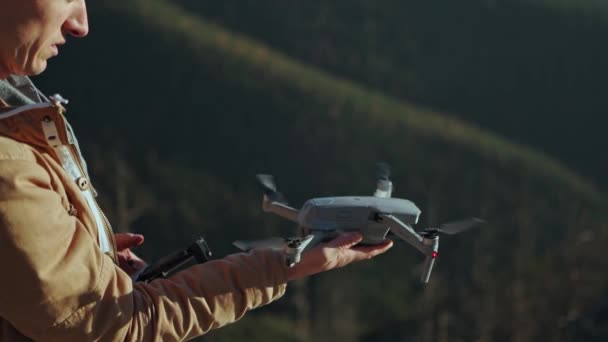 Profesionální letecký videomaker spouští dron z ruky, aby pořídil video nebo fotografii. Muž pilot s ovladačem vypustit vrtulník letadla na obloze, vzlétnout, a vzlétnout. Borovicový les a horská krajina — Stock video