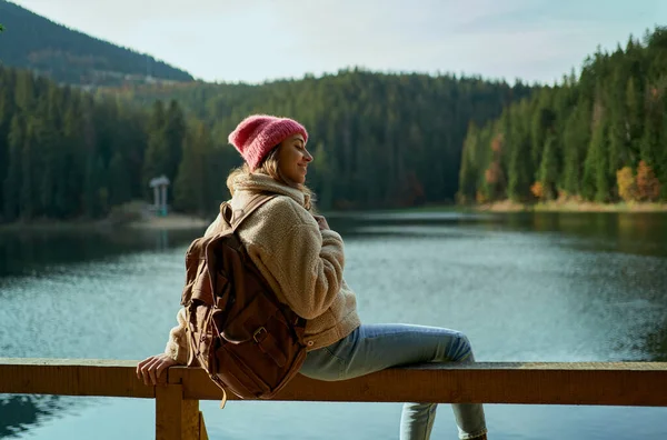 Innoittamana nainen istuu laiturilla vuoristojärvellä ja nauttii matka villi luonto sijainti — kuvapankkivalokuva