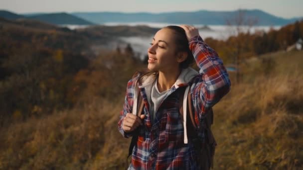 Kamera bevæger sig rundt hipster tusindårig ung kvinde stående på toppen af bjergtoppen ved solopgang, ser fremad, nyder smuk udsigt, glad og beruset på liv, ungdom og lykke – Stock-video