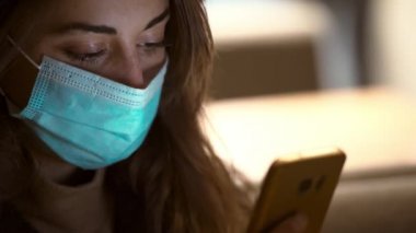 Koruyucu tıbbi maskeli kadını kapatın. Şehir Caddesinde, Bokeh Lights Shining ile Smartphone kullanarak ayakta durun. Sonbahar gecesi açık havada cep telefonu kullanan maskeli bir kadın.