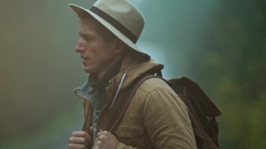 İnsan otostopçunun eski tarz giyinmiş portresi. Sırt çantalı gezgin soğuk ve nemli bir sonbahar gününde dışarıda duruyor ve bir araba bekliyor.