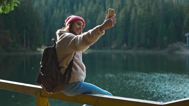 Vrouwelijke Hiker Fotograaf in Woods Shooting Selfie Lake View. Travel Girl hipster Stands in de herfst Natuur Scenic en Filming Zichzelf Op Smartphone Camera, het maken van video-oproep — Stockvideo