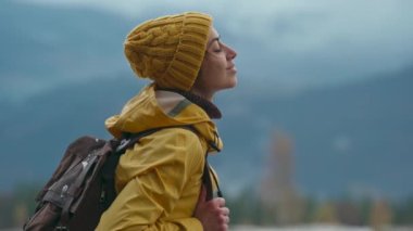 Sarı elbiseli güzel kadın ormanda duruyor, yukarı bakıyor, içine çekiyor ve yağmurdan sonra taze bir nefes alıyor. Seyahat macerası İskandinav turizm konsepti. Yolculuk, gezinti, şehvet havası.