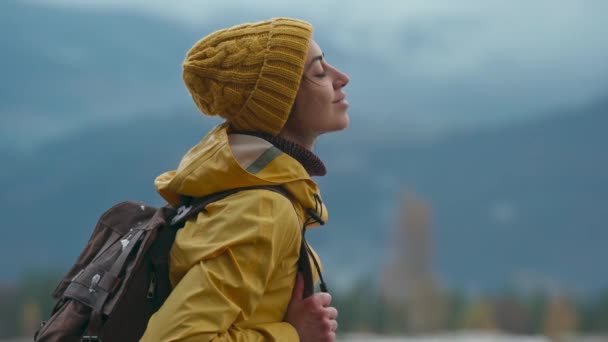 Mulher bonita no desgaste amarelo fica na floresta, olha para cima, inala e respirar fresco após o ar da chuva. Viagem aventura conceito de turismo escandinavo. Roadtrip wanderlust humor — Vídeo de Stock