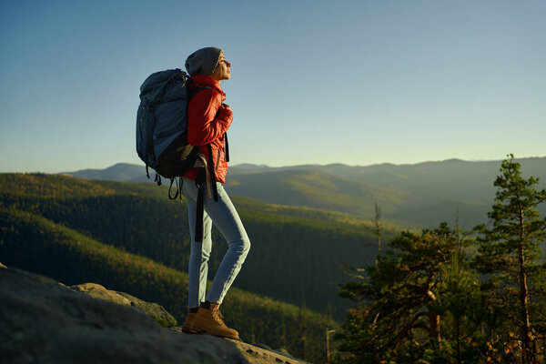 young confident woman enjoying nature, hiking expedition outdoors on top of mountain at sunset.