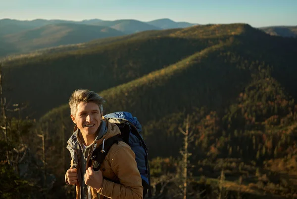 Eventyrmannen nyter naturen og ser glad ut på toppen av fjellet, på fjelltur – stockfoto