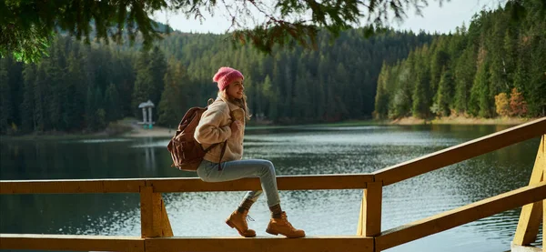 Panoraama maisema kaunis vuoristo järvi metsän ympärillä, nainen vaellus istuu puinen laituri — kuvapankkivalokuva