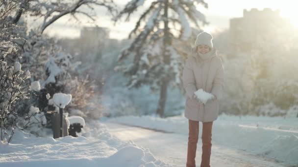 Kış zamanı yürüyüşü ve dışarıda eğlenmek. Neşeli kadın kar yağdırır ve güneşli kış gününde uçan kar taneleriyle sevinir. — Stok video