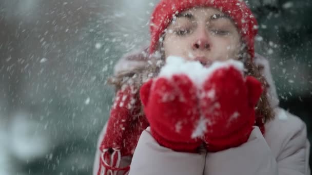 4k slow motion playful laughing woman blows snow from mittens in winter park after snowfall at frosty winter day. happy excited girl enjoying frosty freshness and playing with fresh snow — ストック動画